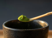 Macro del chashaku de bambu de Matcha Colors midiendo un gramo de matcha verde sobre un cuenco oscuro - campaña IA
