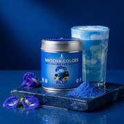 Lata de Blue Matcha Blend sobre piedra azul con latte azul marmoleado, flores de guisante mariposa y polvo azul eléctrico - campaña IA