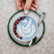 Latte azul con arte de cisne y granos de granada, vista cenital
