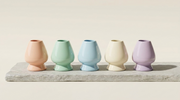 Los cinco colores pastel del soporte de ceramica para chasen de Matcha Colors alineados sobre piedra - campaña IA