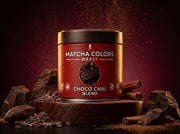 Lata de Choco Chai Blend de Matcha Colors sobre pedestal de madera con trozos de chocolate y cacao en fondo burdeos - campaña IA