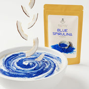 Macro del polvo azul eléctrico de Blue Spirulina formando espirales en yogur de coco, con el doypack detrás - campaña IA