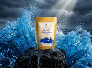 Doypack dorado de Blue Spirulina de Matcha Colors sobre una roca con una ola azul eléctrico rompiendo detrás - campaña IA