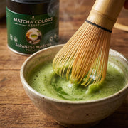 Primer plano del chasen batiendo matcha con espuma fina, lata de Japanese Matcha Premium detrás - campaña IA