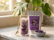 Bolsa de Japanese Ube junto a un latte morado de ube y un cuenco con el polvo, en una cocina con una monstera