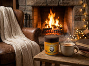 Lata de Masala Chai Blend de Matcha Colors junto a un chai latte humeante frente a una chimenea de invierno - campaña IA