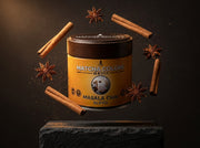 Lata de Masala Chai Blend de Matcha Colors rodeada de canela y anís estrellado levitando en un estudio oscuro - campaña IA
