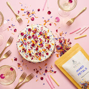 Tarta de celebracion cubierta de Mixed Petals de Matcha Colors como confeti comestible en una mesa rosa de fiesta - campaña IA