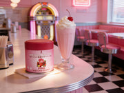 Lata de Pink Matcha Blend junto a un batido rosa con nata en la barra de un diner americano retro en tonos pastel - campaña IA