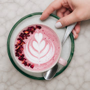 Latte rosa de Pink Matcha Blend con arte de leche y pétalos, vista cenital