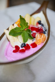 Smoothie bowl de pitaya rosa con frutas, arándanos y menta en cuchara de madera