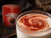 Primer plano de un remolino de rooibos sobre leche, junto a la lata de Rooibos Powder