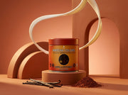 Lata de Vanilla Rooibos Powder de Matcha Colors sobre pedestal terracota con una cinta de leche en el aire - campaña IA