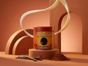 Lata de Vanilla Rooibos Powder de Matcha Colors sobre pedestal terracota con una cinta de leche en el aire - campaña IA