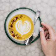 Latte dorado de Yellow Matcha Blend con arte de leche y pétalos, vista cenital